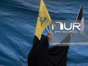 A veiled Iranian woman waves a Palestinian flag and a flag of Lebanon's Hezbollah while participating in an anti-U.S. and anti-Israel rally...