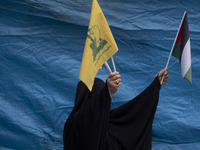 A veiled Iranian woman waves a Palestinian flag and a flag of Lebanon's Hezbollah while participating in an anti-U.S. and anti-Israel rally...