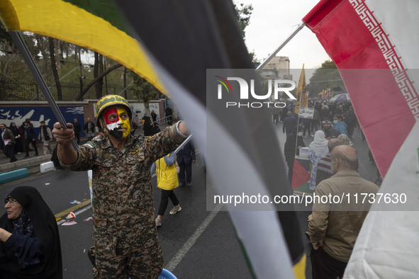 An Iranian demonstrator wears a military uniform and waves an Iranian flag while participating in an anti-U.S. and anti-Israel rally marking...