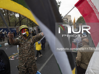 An Iranian demonstrator wears a military uniform and waves an Iranian flag while participating in an anti-U.S. and anti-Israel rally marking...