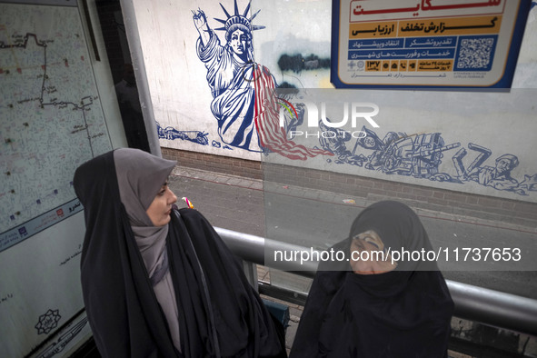 Two veiled Iranian women sit at a bustard in front of an anti-U.S. mural during an anti-U.S. and anti-Israel rally marking the anniversary o...