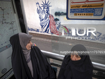 Two veiled Iranian women sit at a bustard in front of an anti-U.S. mural during an anti-U.S. and anti-Israel rally marking the anniversary o...