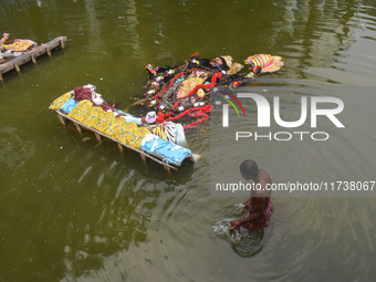 A person bathes next to immersed Kali idols in a pond in Kolkata, India, on November 3, 2024. (