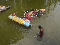 A person bathes next to immersed Kali idols in a pond in Kolkata, India, on November 3, 2024. (