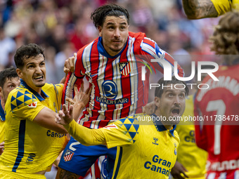 Jose Gimenez of Atletico de Madrid (C) fights for the ball against Alex Munoz (L) and Jose Gomez Campana (R) of UD Las Palmas during the La...