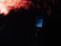 A person takes a picture of the sunset sky in Linkoping, Sweden, on November 3, 2024. (