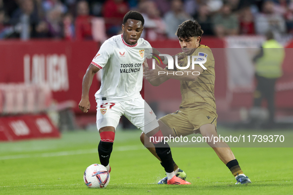 In Seville, Spain, on November 3, 2024, Idumbo of Sevilla FC competes for the ball with Jon Aramburu of Real Sociedad during the La Liga EA...