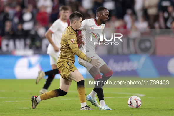 Dodi Lukebakio of Sevilla FC competes for the ball with Igor Zubeldia of Real Sociedad during the La Liga EA Sports match between Sevilla FC...