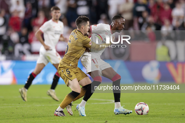 Dodi Lukebakio of Sevilla FC competes for the ball with Igor Zubeldia of Real Sociedad during the La Liga EA Sports match between Sevilla FC...