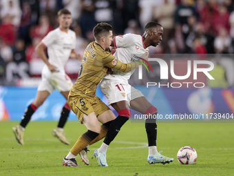 Dodi Lukebakio of Sevilla FC competes for the ball with Igor Zubeldia of Real Sociedad during the La Liga EA Sports match between Sevilla FC...