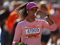 Runner Yiciana Rodriguez of the United States receives a refreshment as she heads up First Avenue during the 2024 New York City Marathon in...