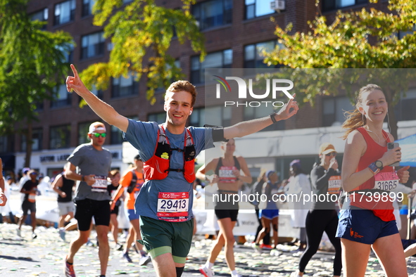 Runner Andrei Strizek of the United States raises his arms in the air as he heads up First Avenue during the 2024 New York City Marathon in...