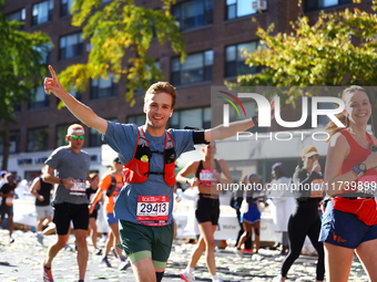 Runner Andrei Strizek of the United States raises his arms in the air as he heads up First Avenue during the 2024 New York City Marathon in...