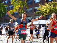 Runner Andrei Strizek of the United States raises his arms in the air as he heads up First Avenue during the 2024 New York City Marathon in...