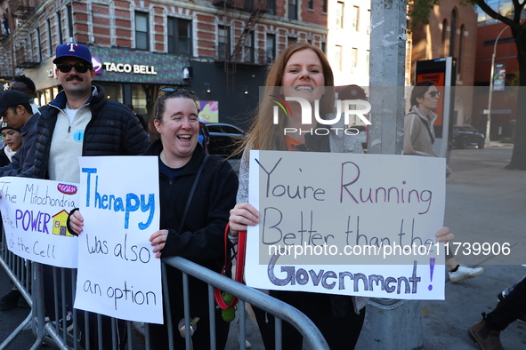 Crowds hold up signs and watch New York City marathon runners as they race up First Avenue in the Upper East Side neighborhood of New York,...