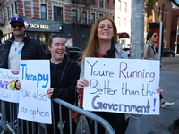 Crowds hold up signs and watch New York City marathon runners as they race up First Avenue in the Upper East Side neighborhood of New York,...