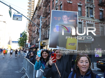 Crowds hold up signs and watch New York City marathon runners as they race up First Avenue in the Upper East Side neighborhood of New York,...