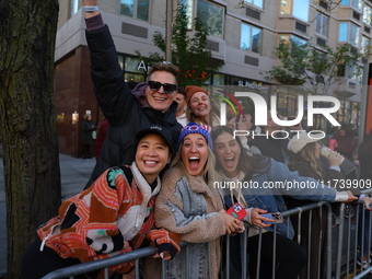 Crowds hold up signs and watch New York City marathon runners as they race up First Avenue in the Upper East Side neighborhood of New York,...