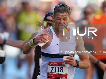 Runner Diarmuid MacDonnell of Ireland splashes himself with water as he runs up First Avenue during the 2024 New York City Marathon in New Y...