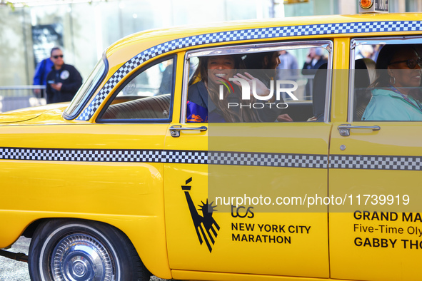 A checkered cab drives Grand Marshall Olympic champion Gabby Thomas up First Avenue during the New York City Marathon in New York City, Unit...