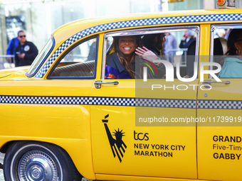 A checkered cab drives Grand Marshall Olympic champion Gabby Thomas up First Avenue during the New York City Marathon in New York City, Unit...