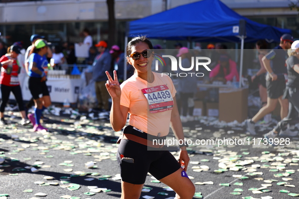 Jonineth Cabague from the Philippines flashes a peace sign as she heads up First Avenue during the New York City Marathon in New York, N.Y.,...