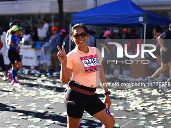 Jonineth Cabague from the Philippines flashes a peace sign as she heads up First Avenue during the New York City Marathon in New York, N.Y.,...