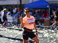 Jonineth Cabague from the Philippines flashes a peace sign as she heads up First Avenue during the New York City Marathon in New York, N.Y.,...