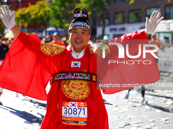 Ju Hyun Kim of South Korea, known as ''The Running King,'' raises his arms in the air as he heads up First Avenue during the 2024 New York C...