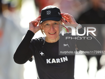 Karin Stoop of Switzerland puts her cap back on after dousing herself as she heads up First Avenue during the 2024 New York City Marathon in...