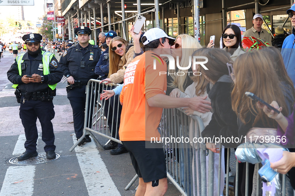 A runner stops to kiss his wife who watches him race during the New York City Marathon in New York City, United States, on November 3, 2024....