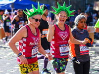 Two runners wearing Statue of Liberty foam headdresses smile as they notice the camera lens pointed at them while running up First Avenue du...