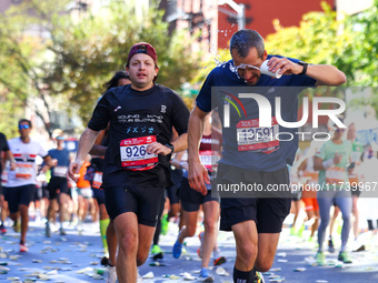 A runner receives some needed relief after dousing himself with water while running up First Avenue during the 2024 New York City Marathon i...