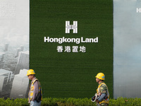 Workers pass by the construction site of the West Bund Financial City near the Hongkong Land corporate logo outside the fence in Shanghai, C...