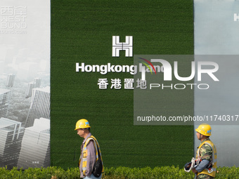 Workers pass by the construction site of the West Bund Financial City near the Hongkong Land corporate logo outside the fence in Shanghai, C...