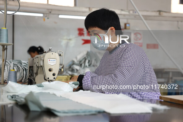 Workers make down jackets at a workshop of a garment manufacturer in Hehe town, Yangxin county, Binzhou city, East China's Shandong province...