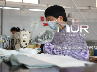 Workers make down jackets at a workshop of a garment manufacturer in Hehe town, Yangxin county, Binzhou city, East China's Shandong province...