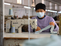 Workers make down jackets at a workshop of a garment manufacturer in Hehe town, Yangxin county, Binzhou city, East China's Shandong province...