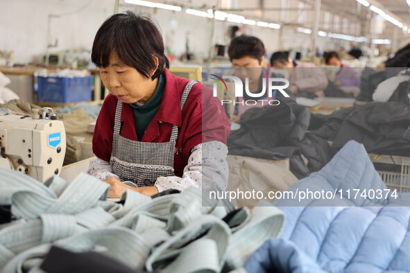 Workers make down jackets at a workshop of a garment manufacturer in Hehe town, Yangxin county, Binzhou city, East China's Shandong province...