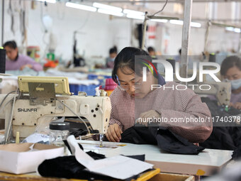 Workers make down jackets at a workshop of a garment manufacturer in Hehe town, Yangxin county, Binzhou city, East China's Shandong province...