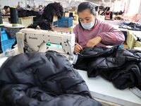 Workers make down jackets at a workshop of a garment manufacturer in Hehe town, Yangxin county, Binzhou city, East China's Shandong province...