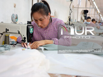 Workers make down jackets at a workshop of a garment manufacturer in Hehe town, Yangxin county, Binzhou city, East China's Shandong province...