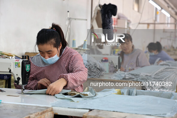 Workers make down jackets at a workshop of a garment manufacturer in Hehe town, Yangxin county, Binzhou city, East China's Shandong province...