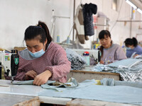 Workers make down jackets at a workshop of a garment manufacturer in Hehe town, Yangxin county, Binzhou city, East China's Shandong province...