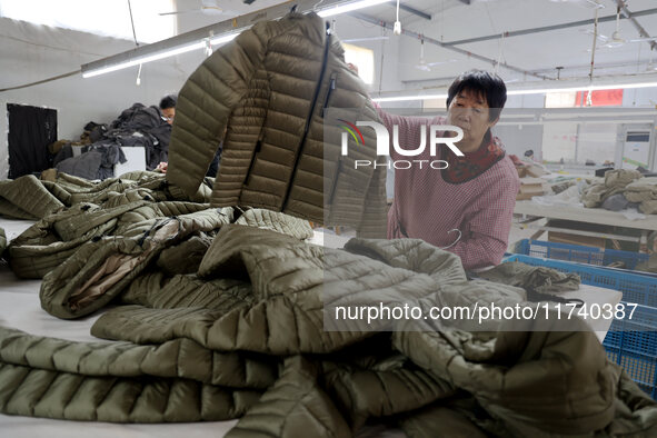 Workers make down jackets at a workshop of a garment manufacturer in Hehe town, Yangxin county, Binzhou city, East China's Shandong province...