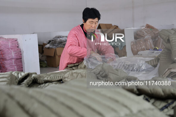 Workers make down jackets at a workshop of a garment manufacturer in Hehe town, Yangxin county, Binzhou city, East China's Shandong province...