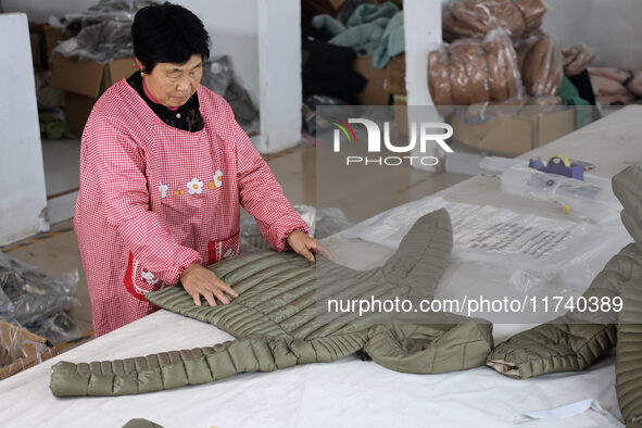 Workers make down jackets at a workshop of a garment manufacturer in Hehe town, Yangxin county, Binzhou city, East China's Shandong province...