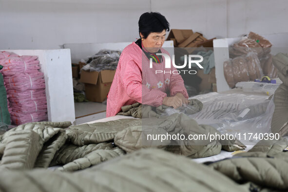 Workers make down jackets at a workshop of a garment manufacturer in Hehe town, Yangxin county, Binzhou city, East China's Shandong province...