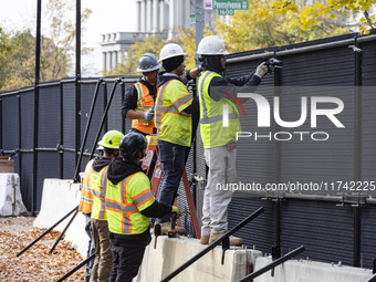 Workers erect security fences surrounding the construction site for the 2025 Presidential Inaugural Parade Reviewing Stand in Lafayette Squa...