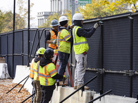 Workers erect security fences surrounding the construction site for the 2025 Presidential Inaugural Parade Reviewing Stand in Lafayette Squa...